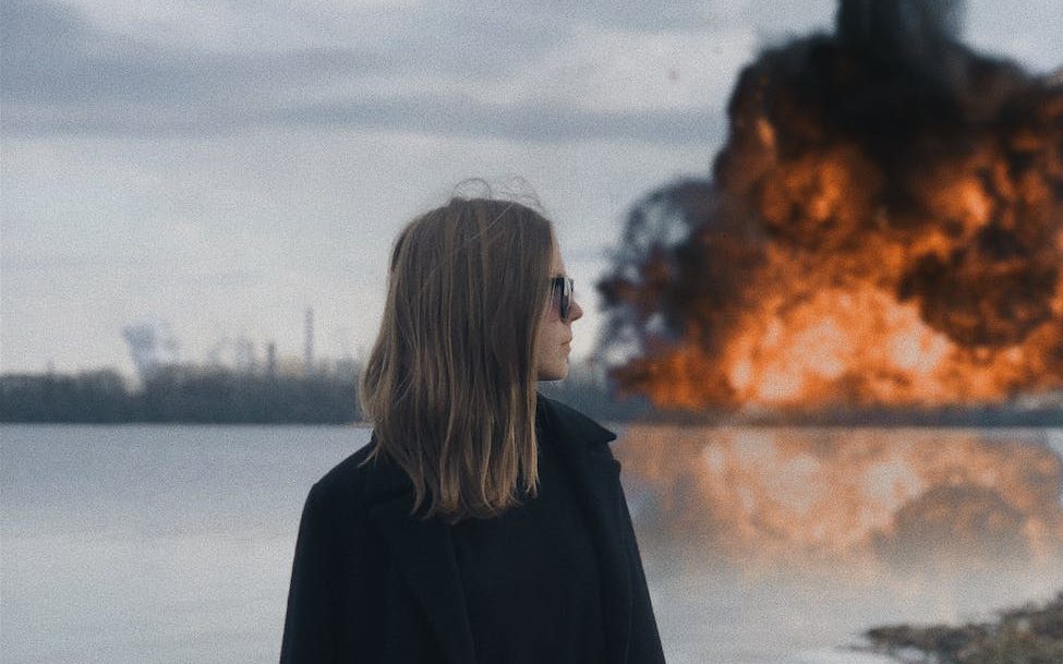 woman in black coat standing near body of water